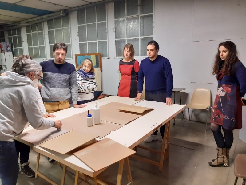 Les adultes de la troupe Les Pièces Montées participent à un atelier pour créer leur décor en carton